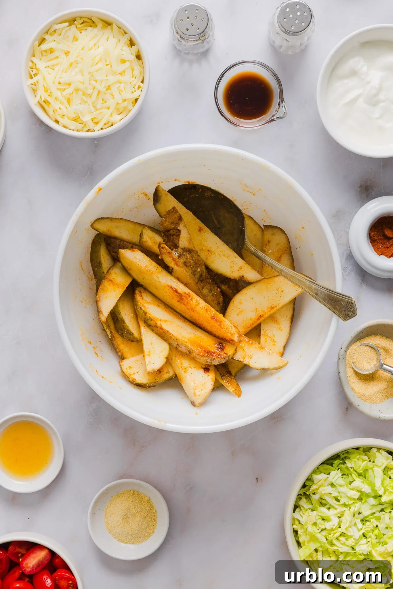 Raw potato wedges in a bowl with seasonings.