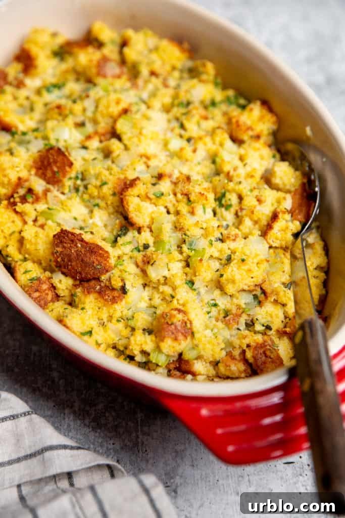 Gluten-Free Cornbread Stuffing Recipe (Cornbread Dressing) 2 Gluten free cornbread stuffing in a baking dish with a serving spoon.