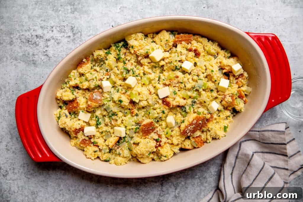 Gluten-Free Cornbread Stuffing Recipe (Cornbread Dressing) 9 Uncooked cornbread stuffing in a baking dish, dotted with butter.