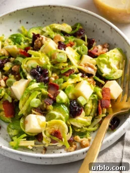 closeup 45 degree angle shot of a serving of brussel sprout salad with a gold fork.