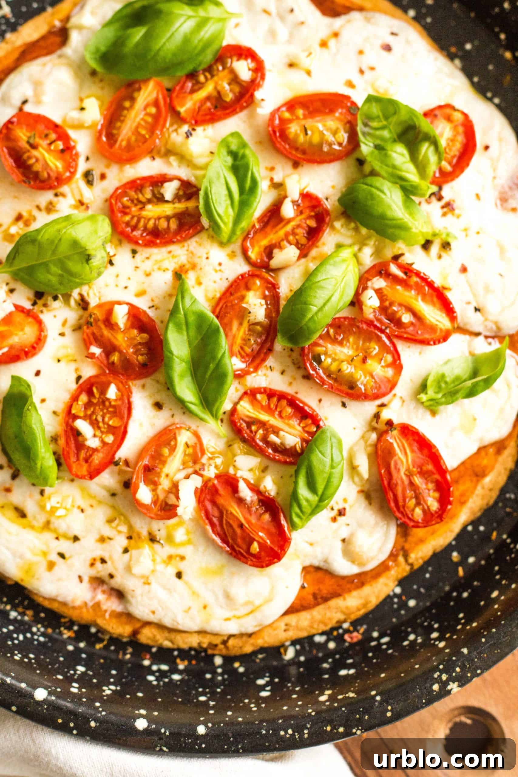 Freshly baked gluten-free caprese pizza on a pizza pan.