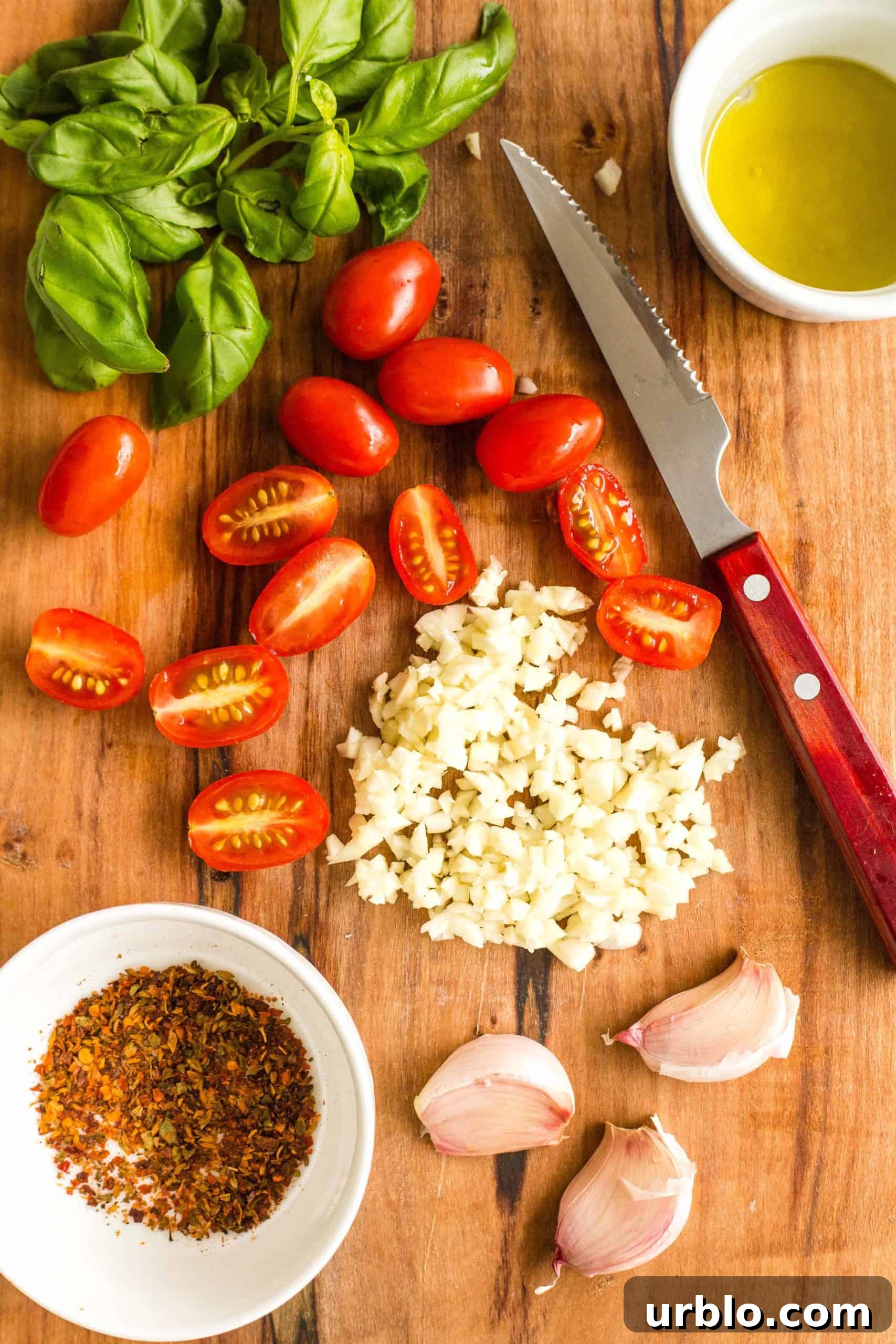 Preparing the topping ingredients for caprese pizza - basil leaves, cherry tomatoes, minced garlic, red chili flakes, olive oil.