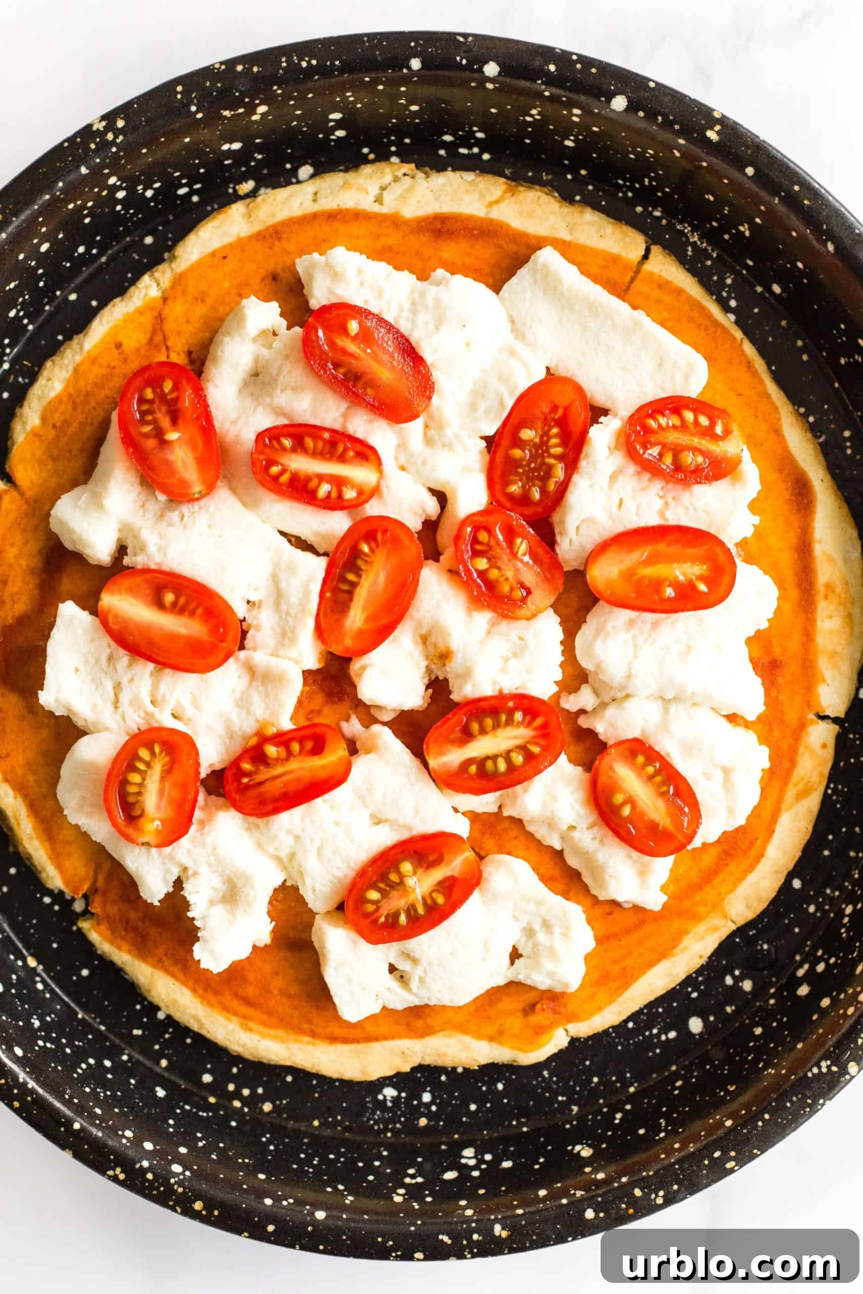 Gluten-free pizza crust with mozzarella cheese and cherry tomato halves.