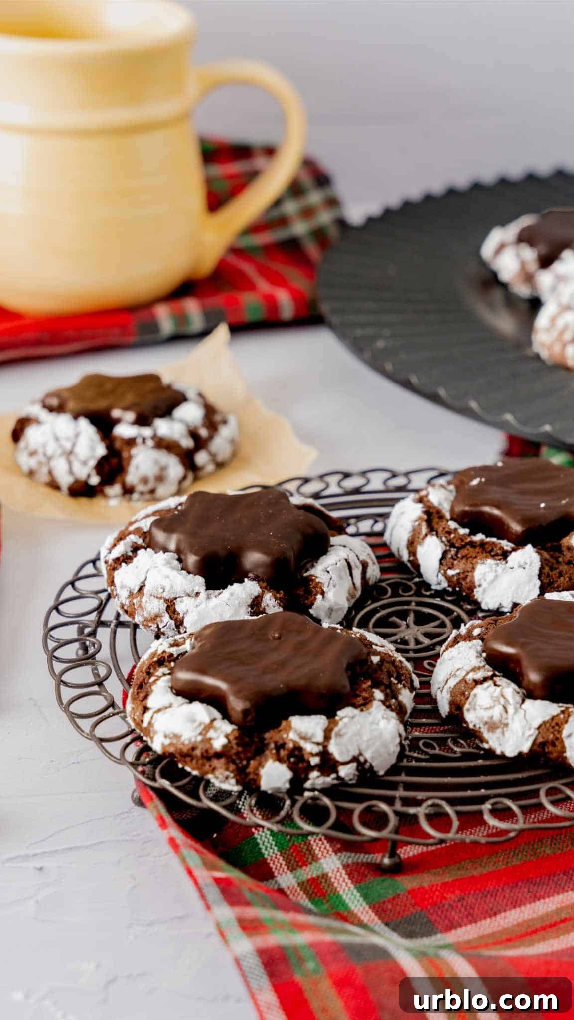 Four hot cocoa crinkle cookies with peppermint patties sitting on a round black cooling rack.
