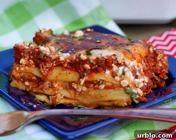 A slice of lasagna on a blue plate with a copper fork.