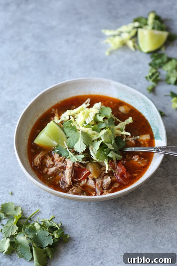 pozole rojo recipe in a bowl with cilantro and lime
