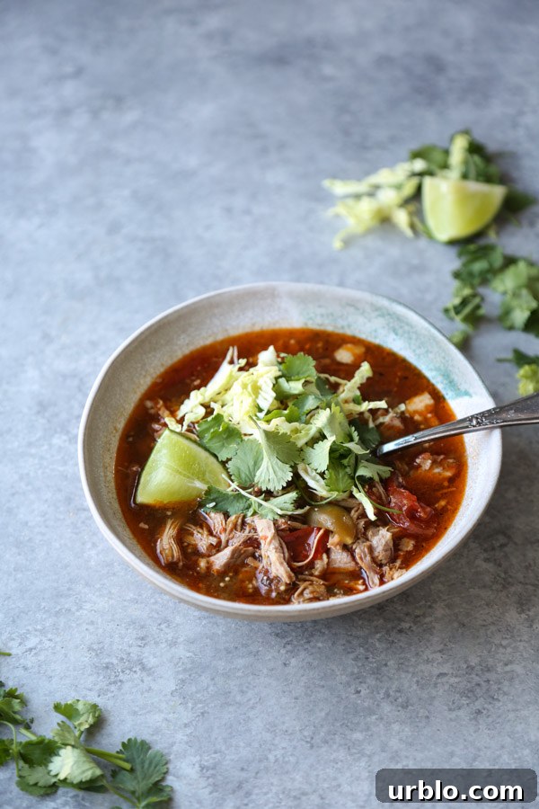 pozole rojo recipe in a bowl with cilantro and lime