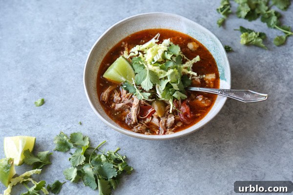 pozole rojo recipe in a bowl with cilantro and lime