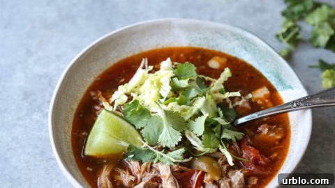 pozole rojo recipe in a bowl with cilantro and lime