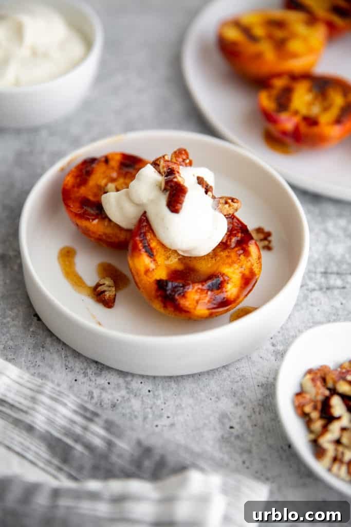 Grilled peaches in a bowl topped with whipped cream and pecans. 
