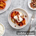 Grilled peaches on a plate topped with cardamom whipped cream and toasted nuts.