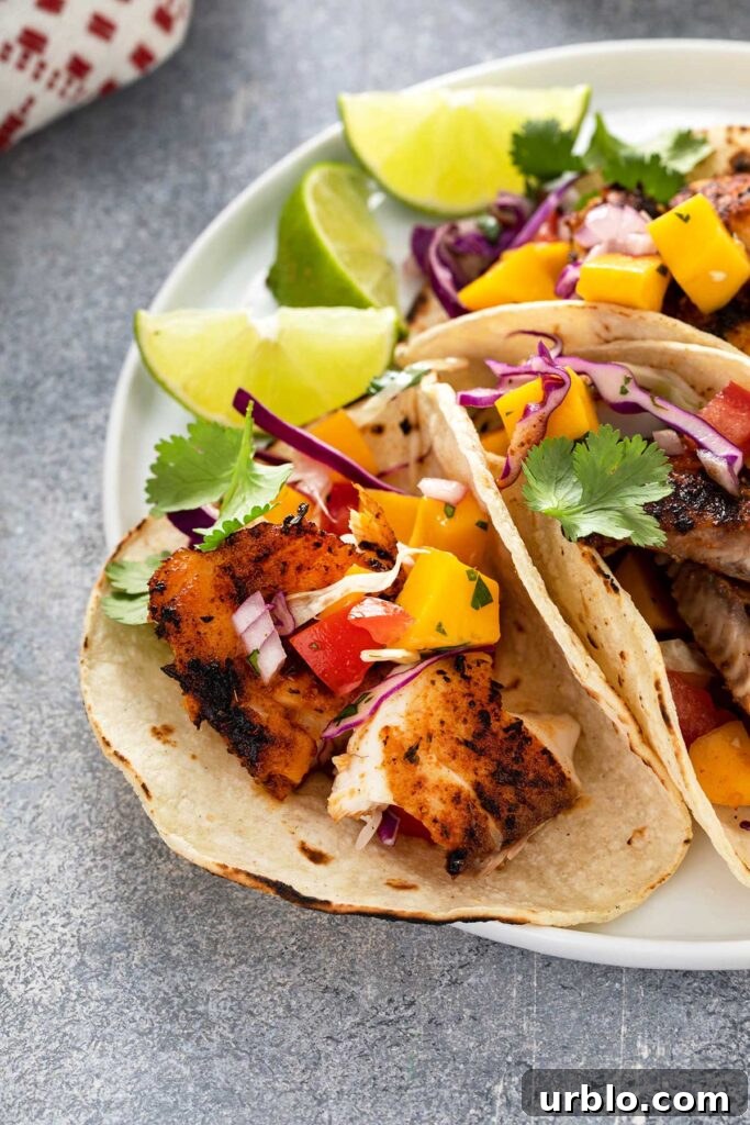 Blackened Fish Tacos with mango slaw, decorated with slices of lime and garnished with cilantro.