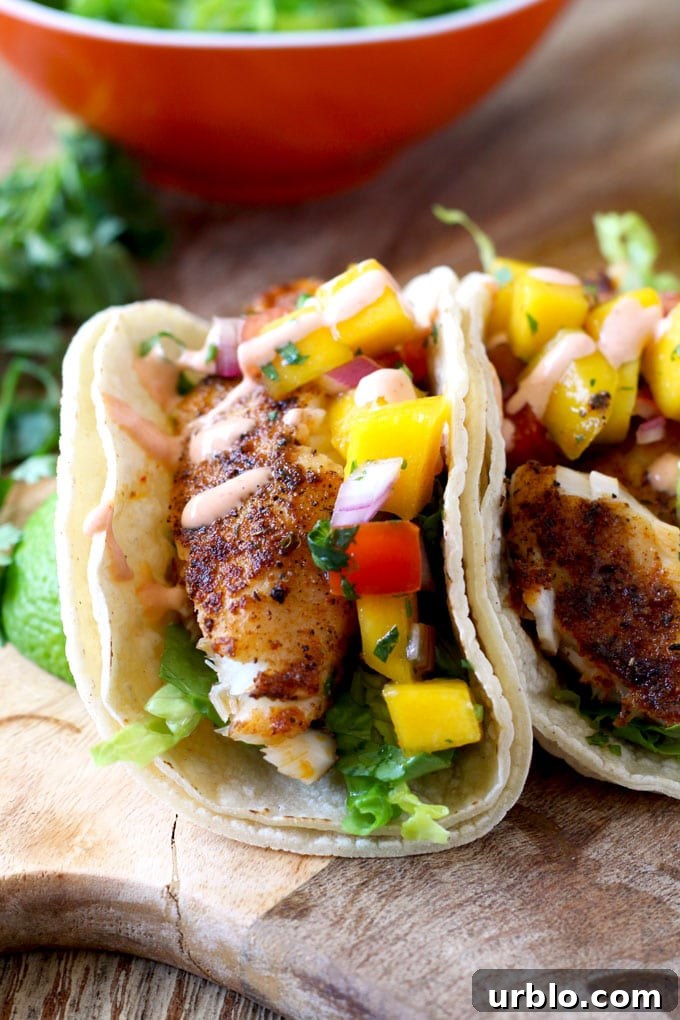 Close up of Blackened Fish Tacos with Mango Salsa and Sriracha Aioli on a wooden surface