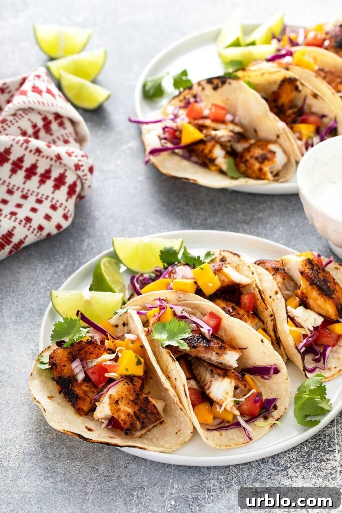 Blackened Fish Tacos with mango slaw, decorated with slices of lime and garnished with cilantro.