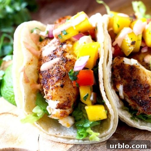 Close up of Blackened Fish Tacos with Mango Salsa and Sriracha Aioli on a wooden surface