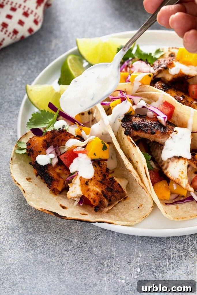 Pouring lime crema with a spoon over a blackened fish taco.