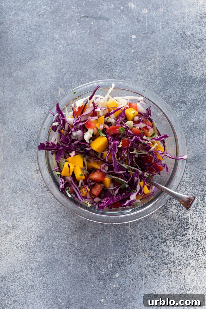 Mango Slaw ingredients mixed in a glass bowl for blackened tacos.