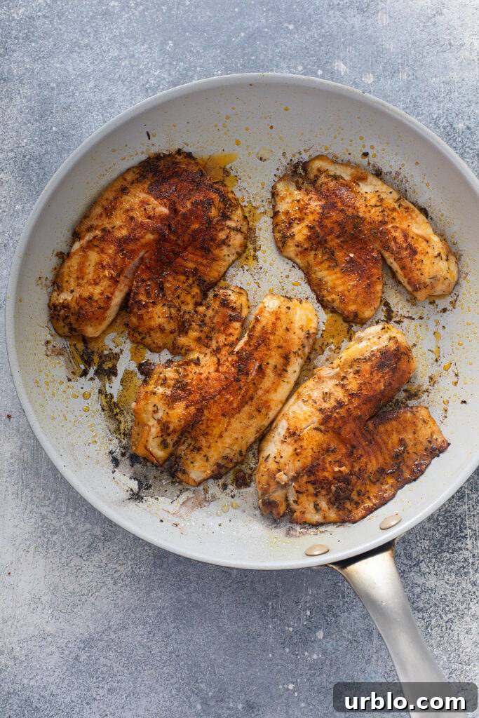 Crispy delicious blackened fish cooked in pan.