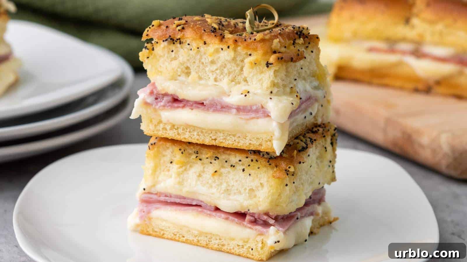21 Crowd-Pleasing Potluck Recipes That Outshine Store-Bought Dishes 20 Two stacked sandwiches with layers of ham and melted cheese between thick slices of seasoned bread, served on a white plate.