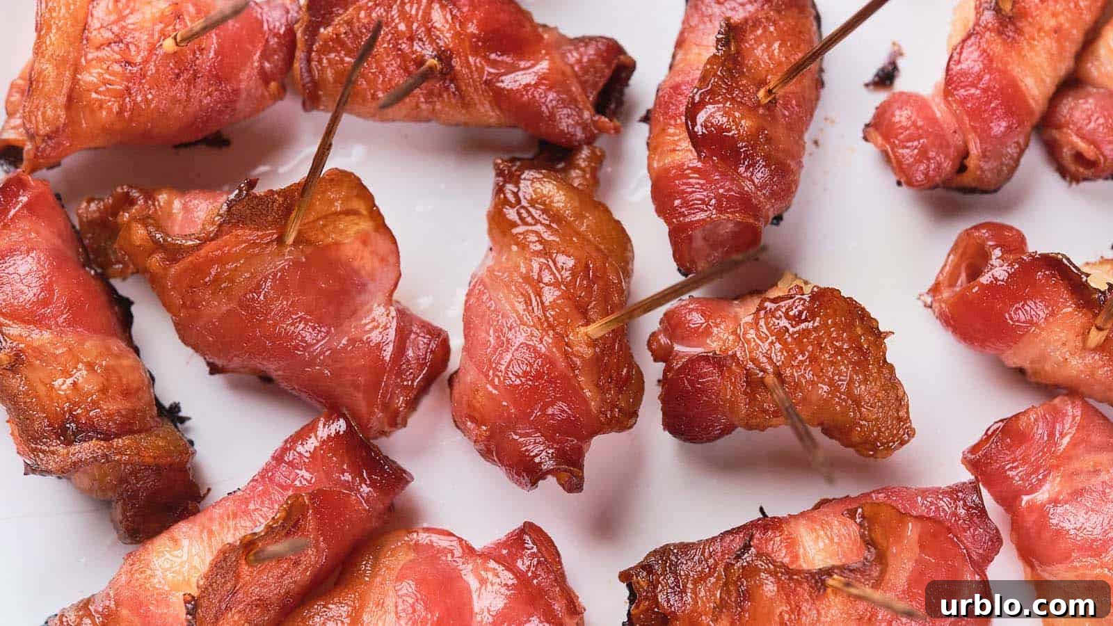 21 Crowd-Pleasing Potluck Recipes That Outshine Store-Bought Dishes 10 Close-up of several bacon-wrapped items secured with toothpicks, arranged on a white surface.