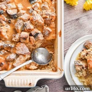A spoon is in the pan with the sourdough bread pudding and a portion of the pudding is on a plate.