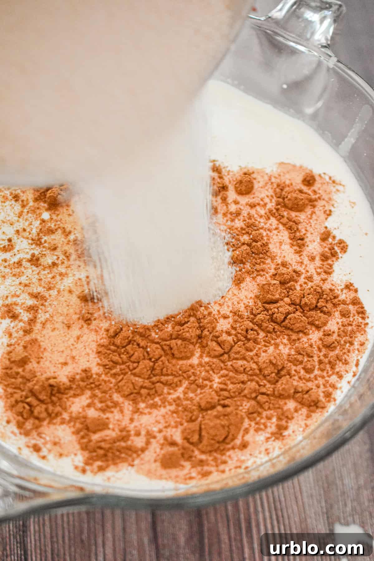 Sugar is added to the bowl full of milk.