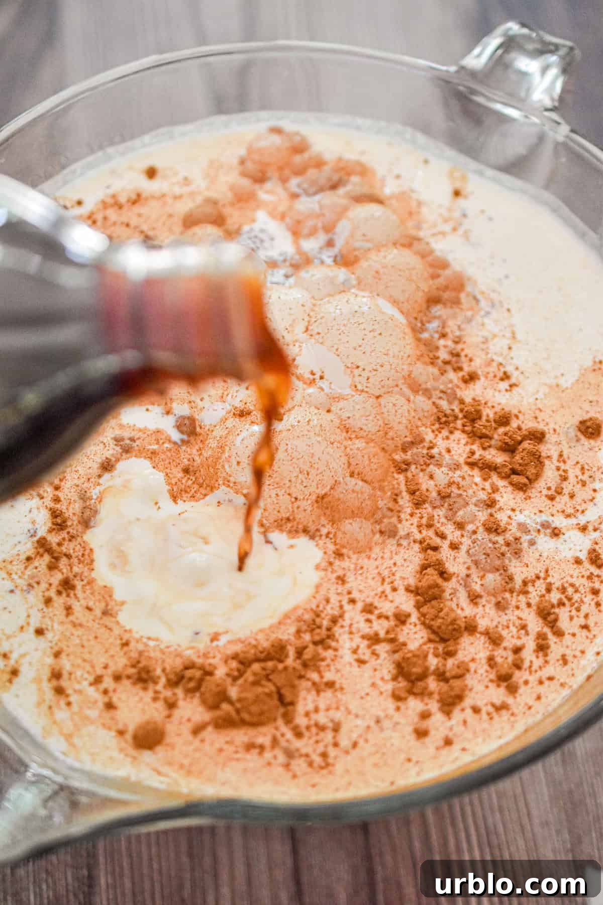 Vanilla is being poured into the liquid measuring cup.
