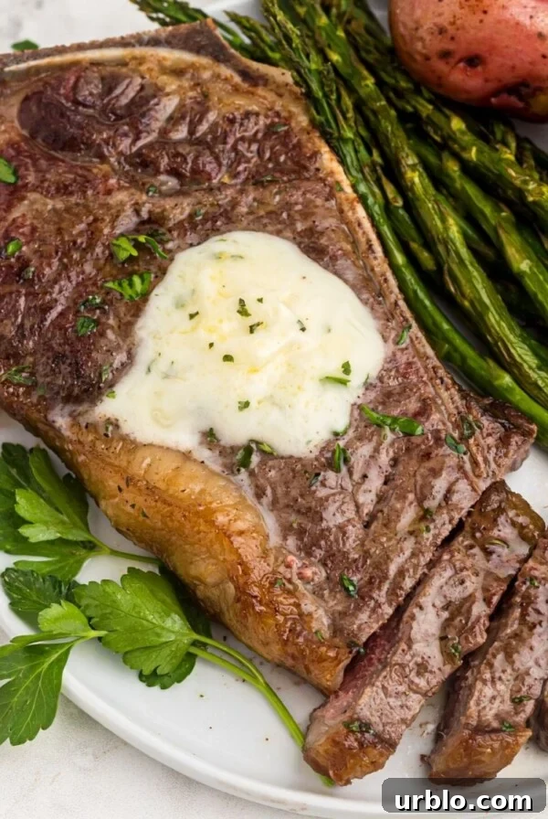 Juicy garlic on a white plate with asparagus and potatoes, the steak is sliced with a fork