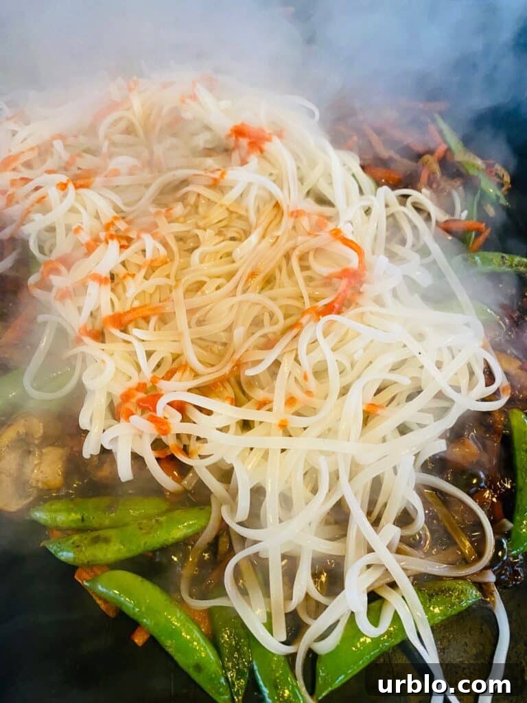 adding noodles and sauce to the griddle