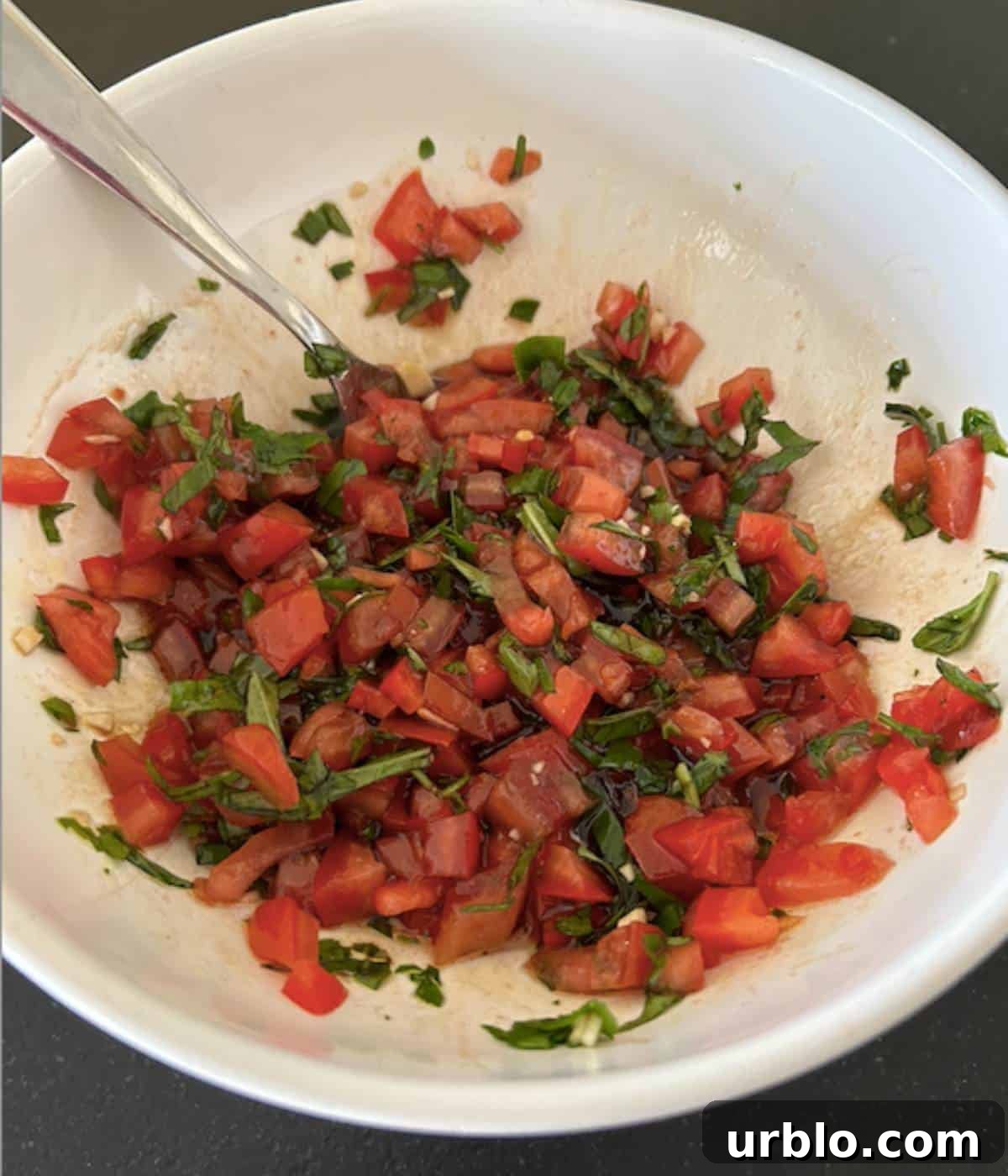 Bruschetta ingredients with balsamic and olive oil in bowl.