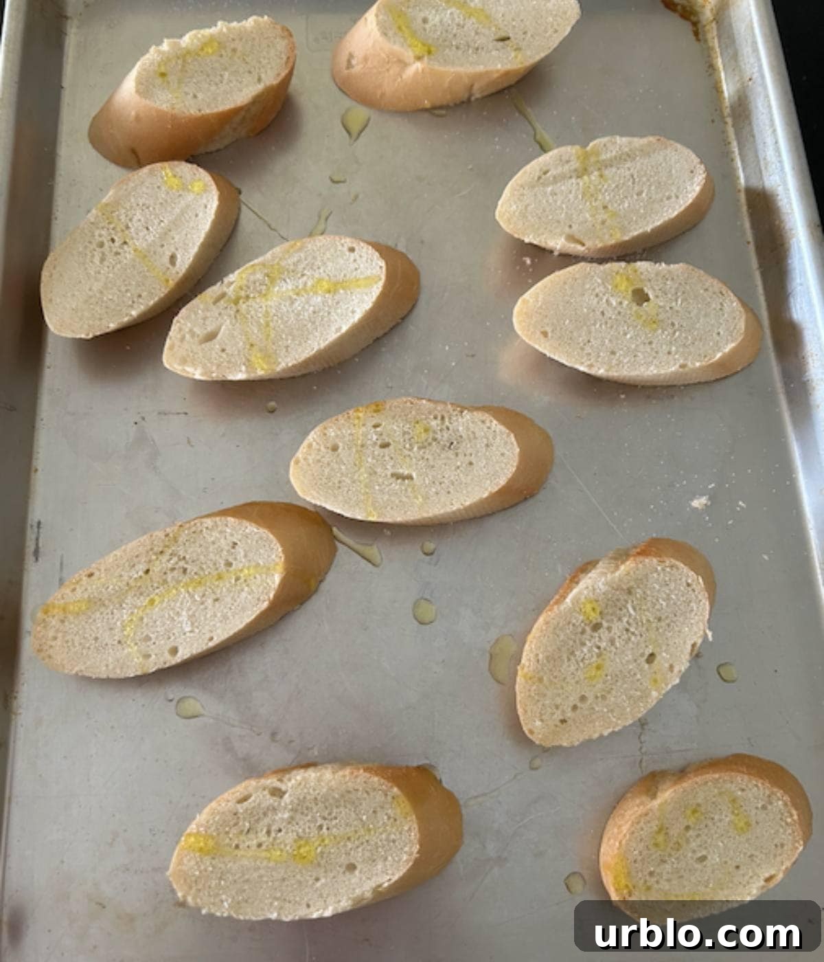 French bread sliced and ready to bake on cookie sheet.