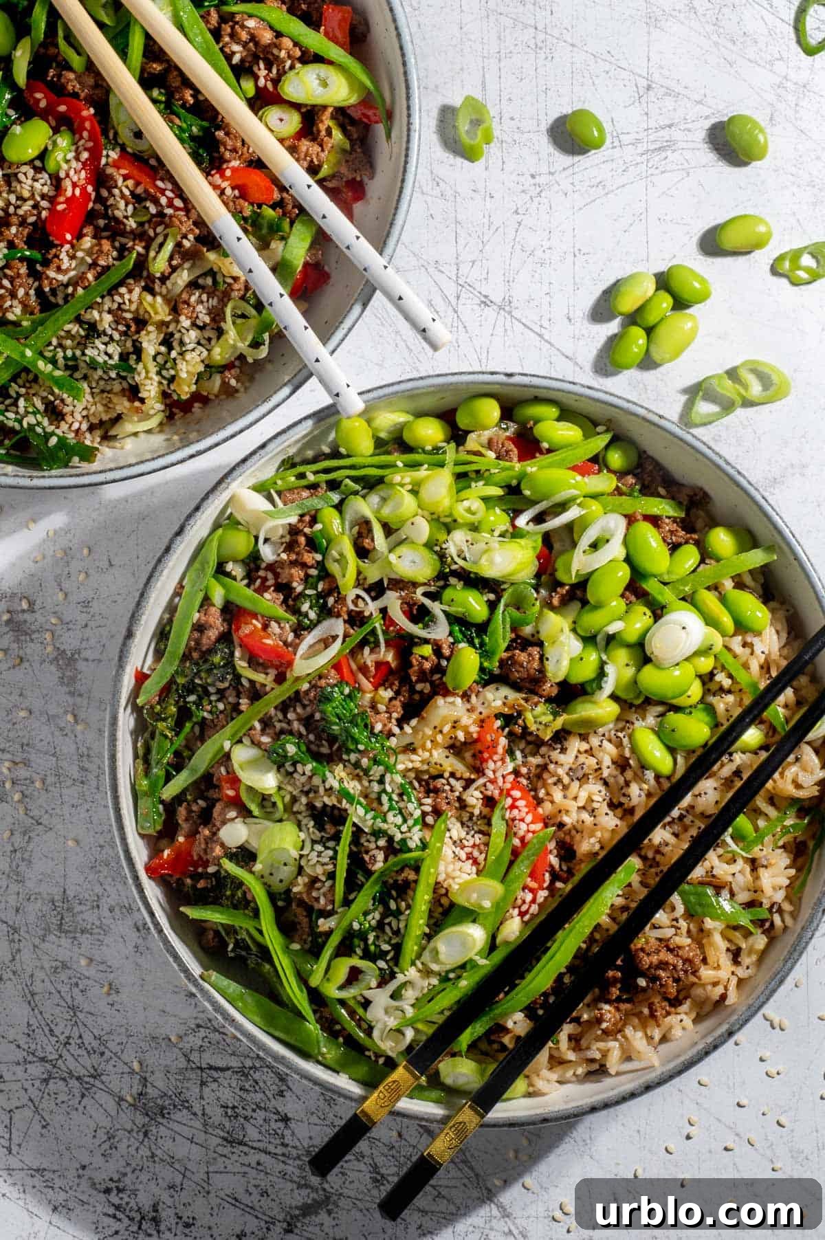 Two beef teriyaki bowls on a white background with chopsticks.