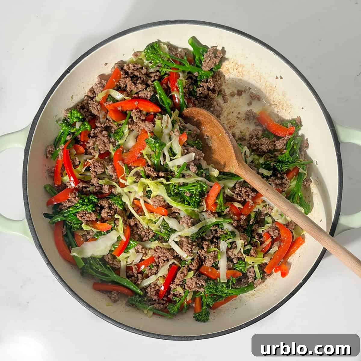 Frying the vegetables together with the ground beef in a large frying pan.