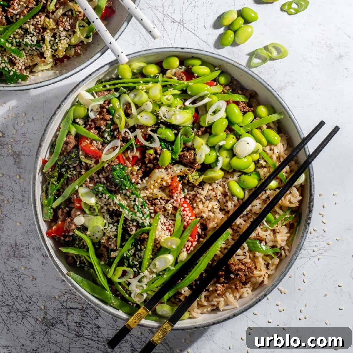 Two beef teriyaki bowls on a white background with chopsticks.