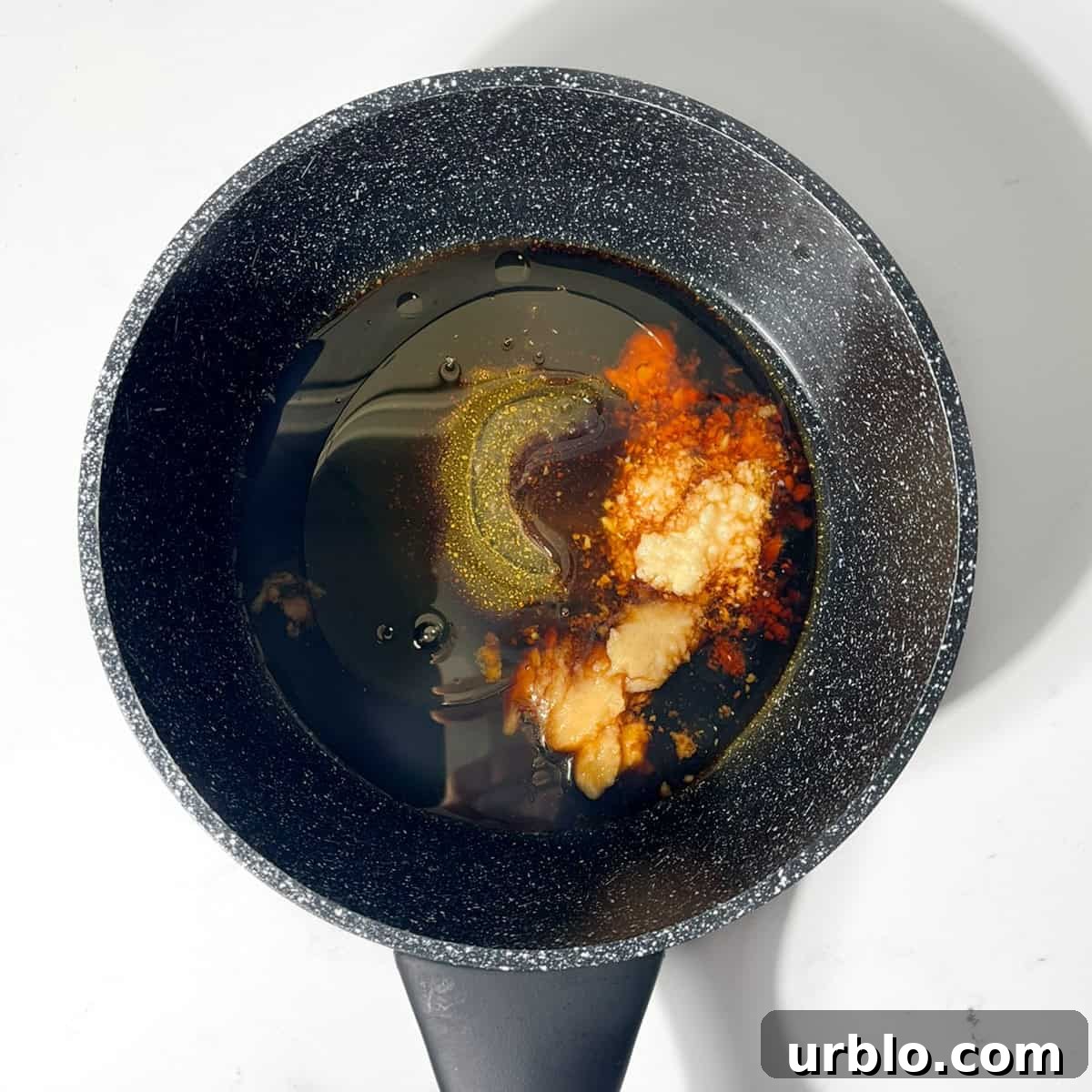 Placing all the ingredients for the teriyaki sauce in a small black saucepan.