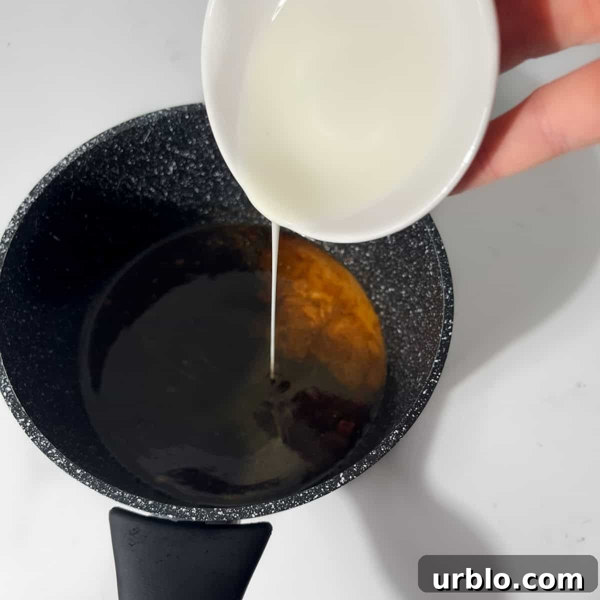 Adding cornstarch to the teriyaki sauce in a small saucepan.