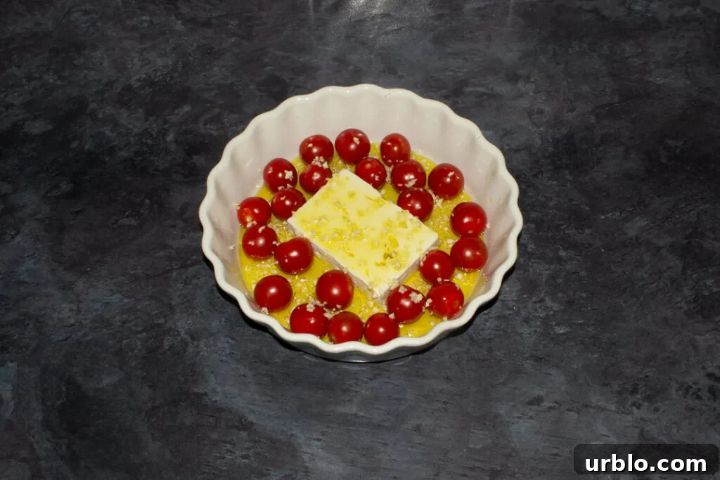 Tomatoes, a block of feta and garlic covered in olive oil in a dish