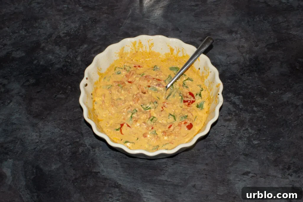 Baked feta tomato pasta sauce in an ovenproof dish with basil stirred through it.