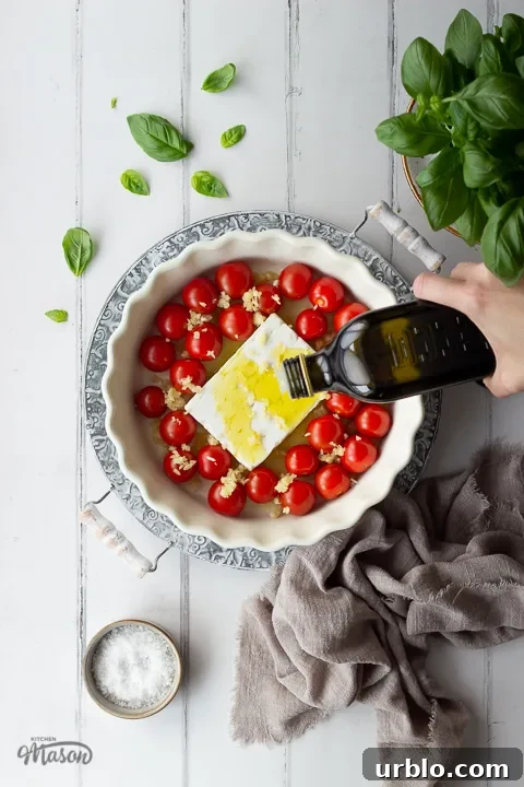 Olive oil being poured over feta, tomatoes and garlic.