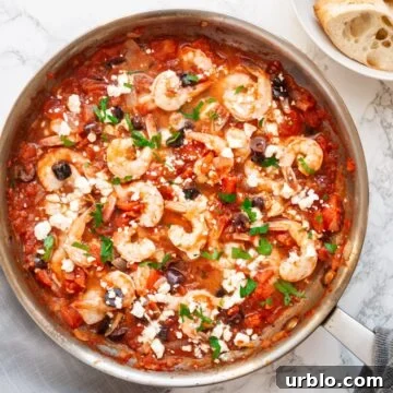 A top down view of Greek shrimp with tomatoes and feta cheese in a skillet.