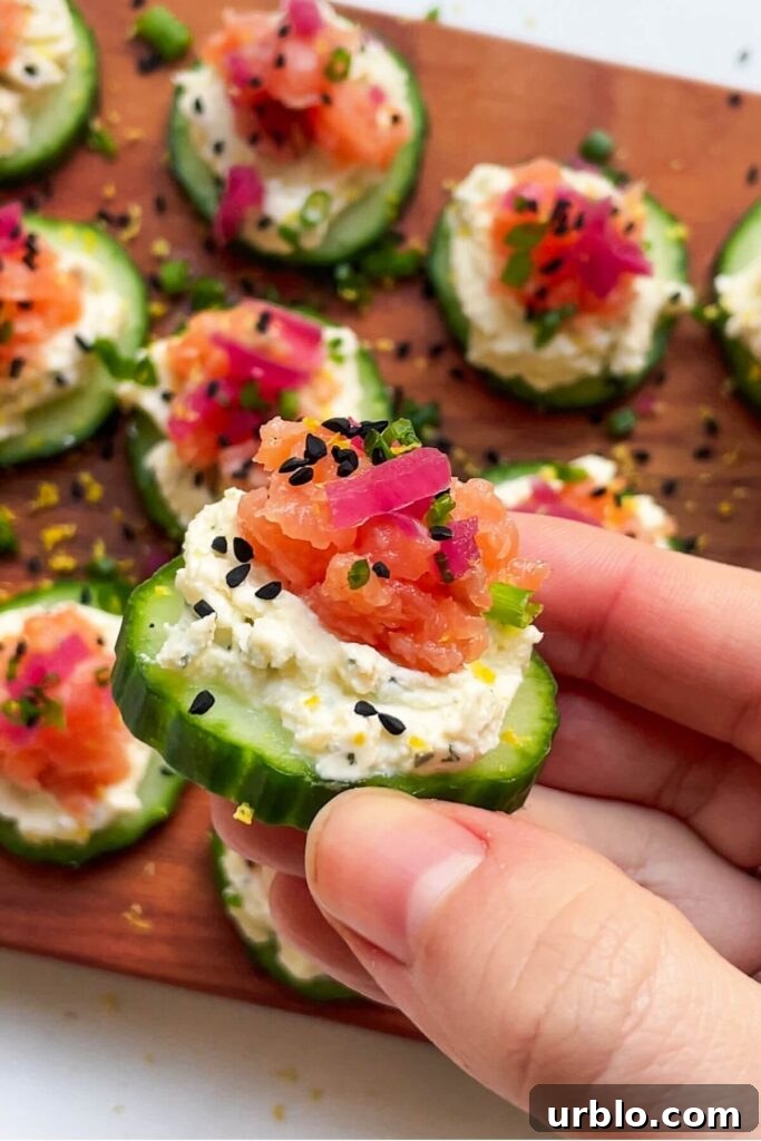 Close up of hand holding up smoked salmon cucumber bite.
