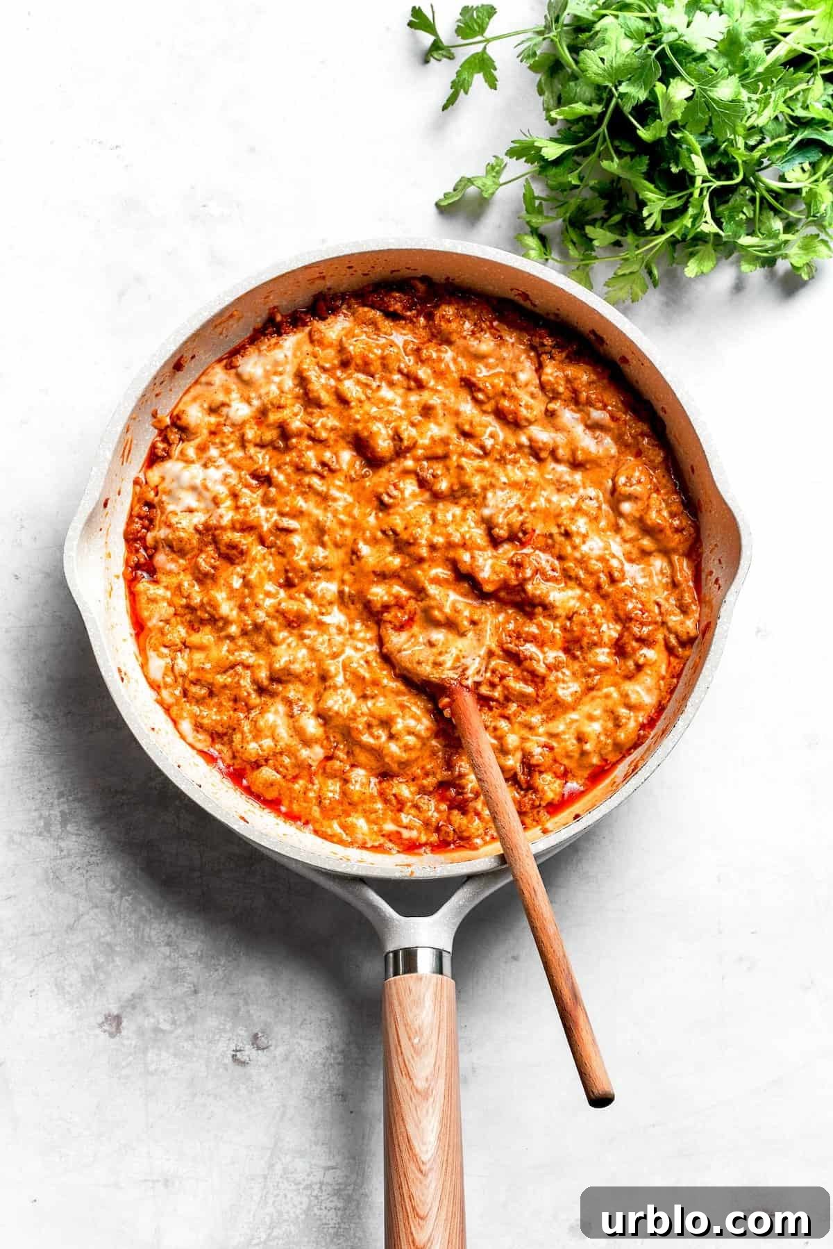 Dorito casserole filling in a skillet with a spoon.