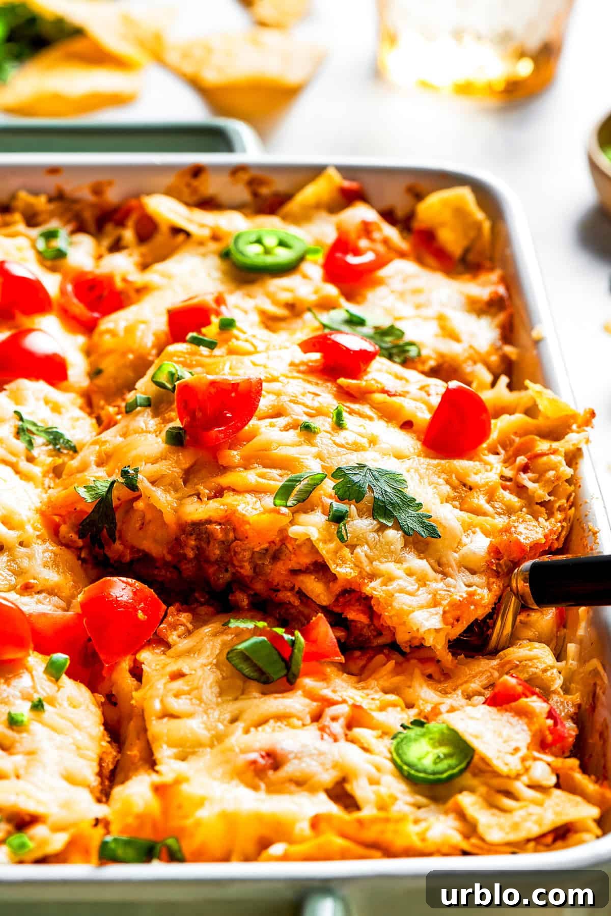 Side shot of a casserole topped with melted cheese, halved cherry tomatoes, and fresh greens.