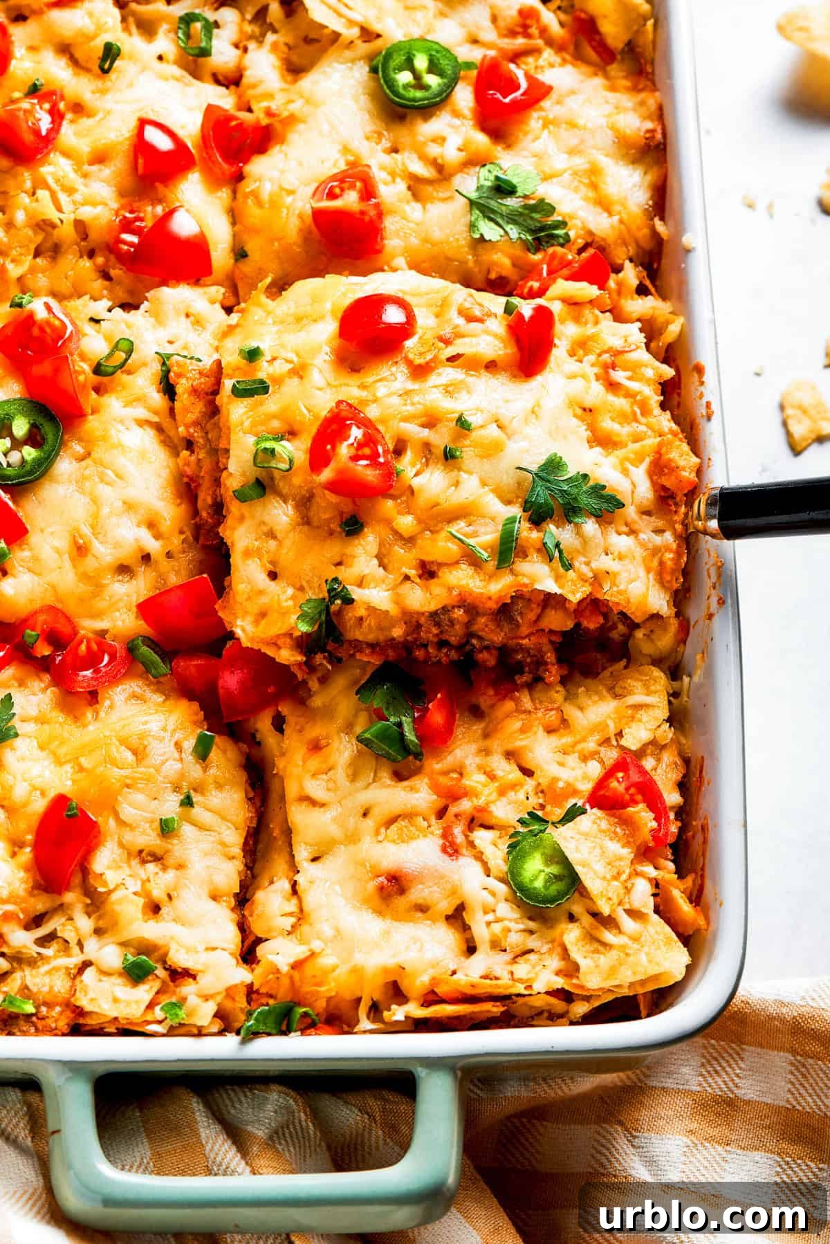 A serving utensil lifts out a scoop of Dorito casserole.