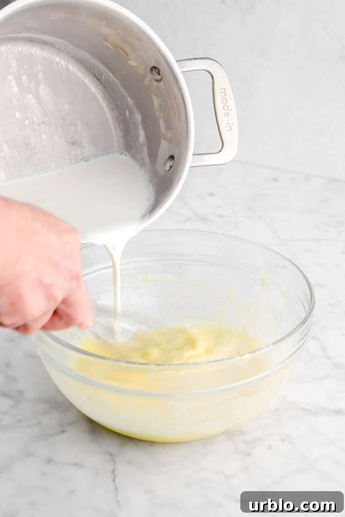 heated cream being poured into egg yolk mixture