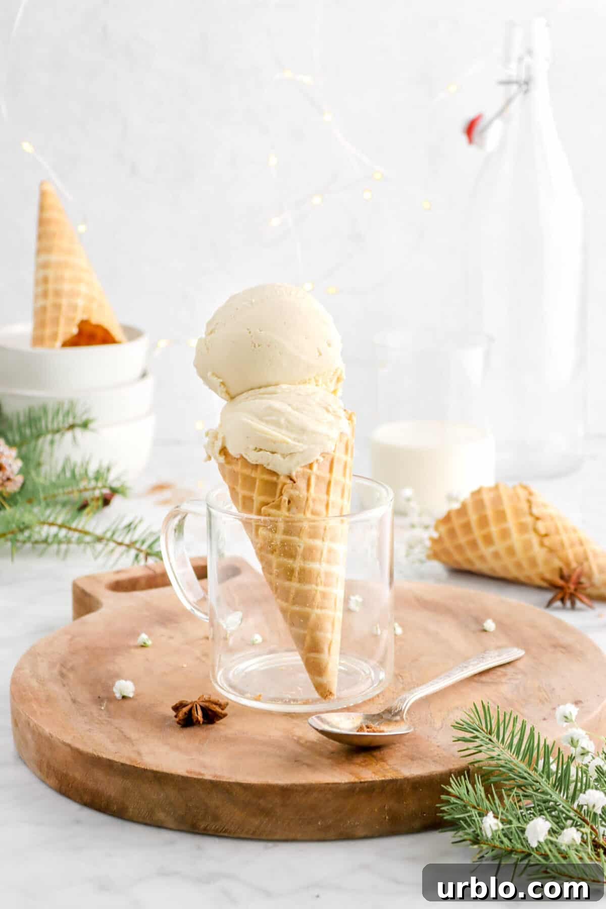 two scoops of eggnog ice cream in waffle cone on wood serving board