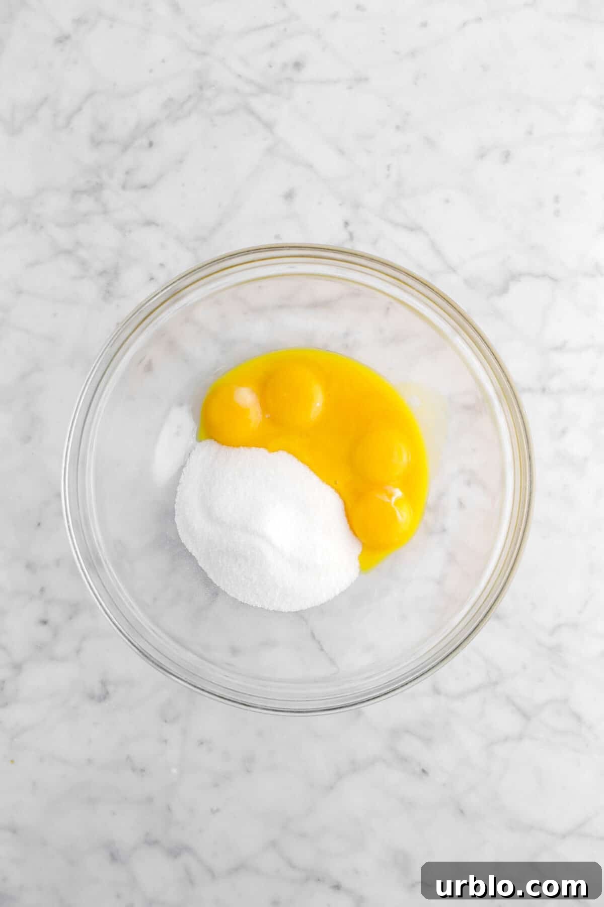 egg yolks and sugar in glass bowl