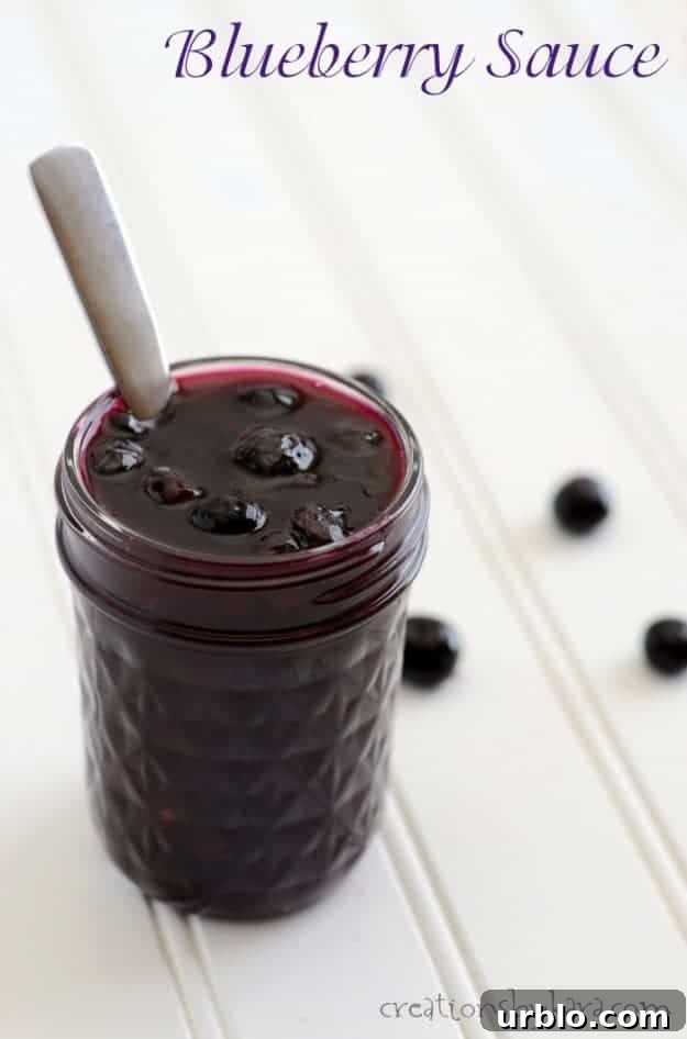 jar of blueberry topping on a white tabletop with blueberries in the background