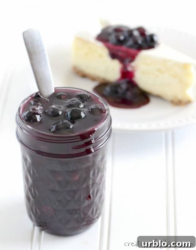 jar of Homemade Blueberry Sauce in front of a slice of cheesecake