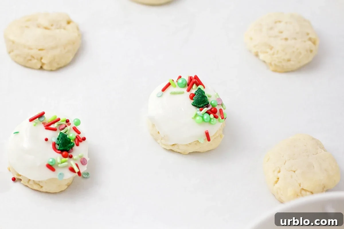 Cookies topped with white frosting and sprinkles.